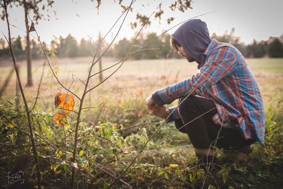 a picture of man in a field, with a hoodie on.
